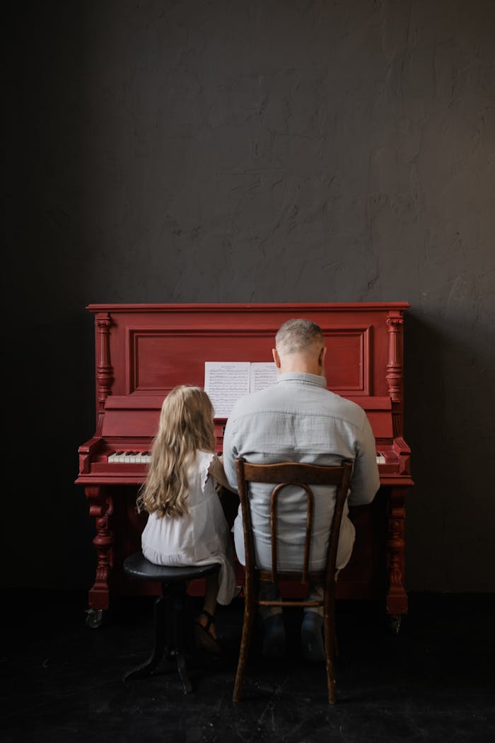 Elderly man and young girl bonding over music while playing piano indoors